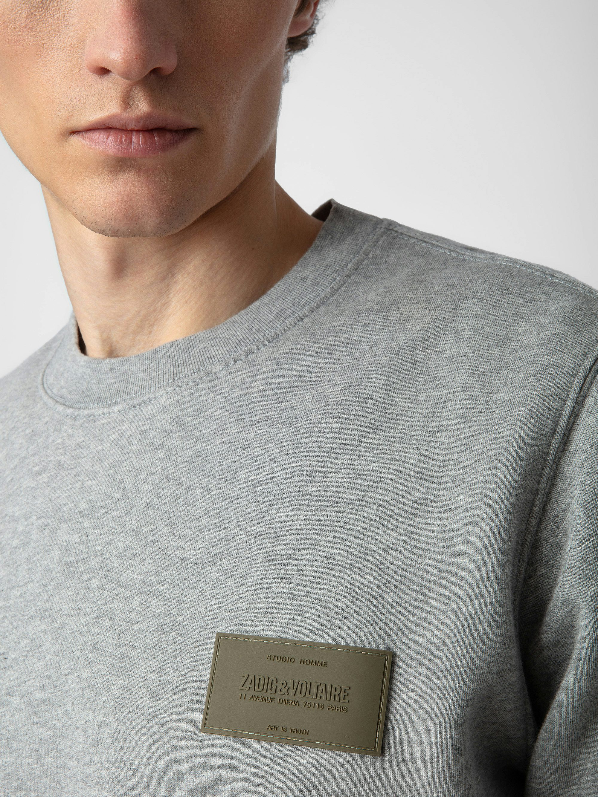 Sudadera Aime - Sudadera en color gris jaspeado con mangas largas, cuello redondo y parche decorativo en el pecho.